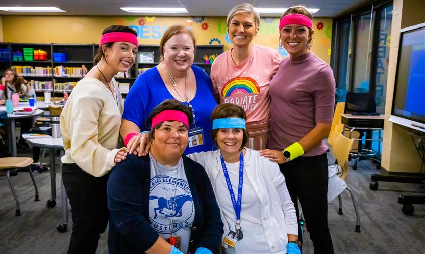 Teachers pose while wearing neon sweatbands